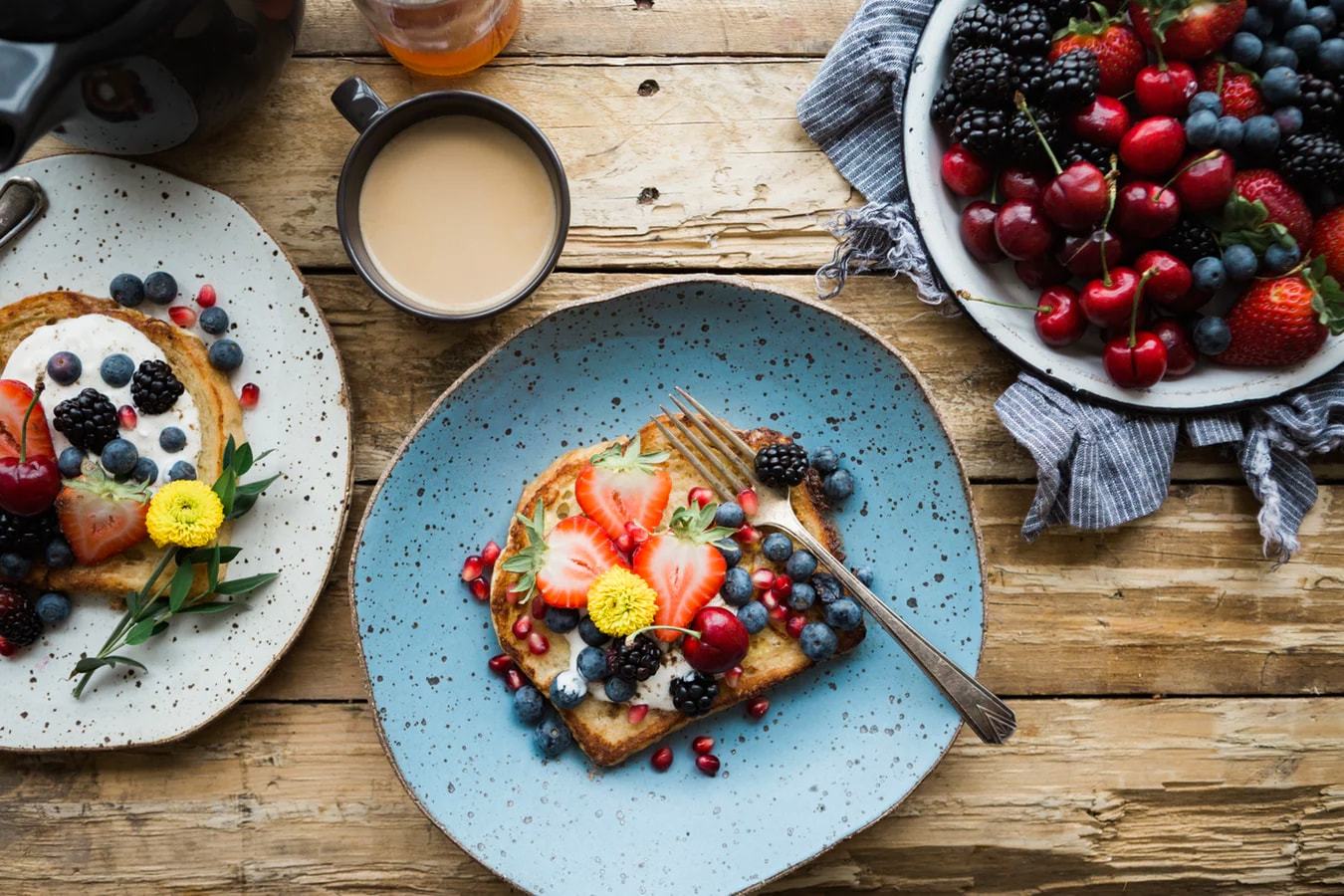 French toast, berries and coffee on a wooden breakfast table