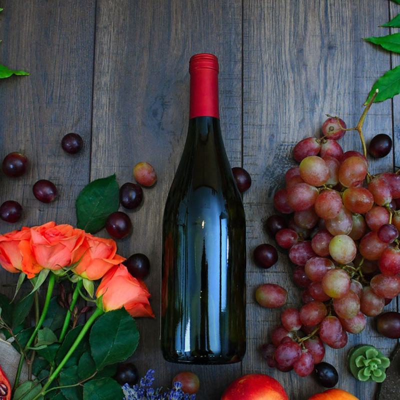 Bottle of red wine with grapes on a wooden table