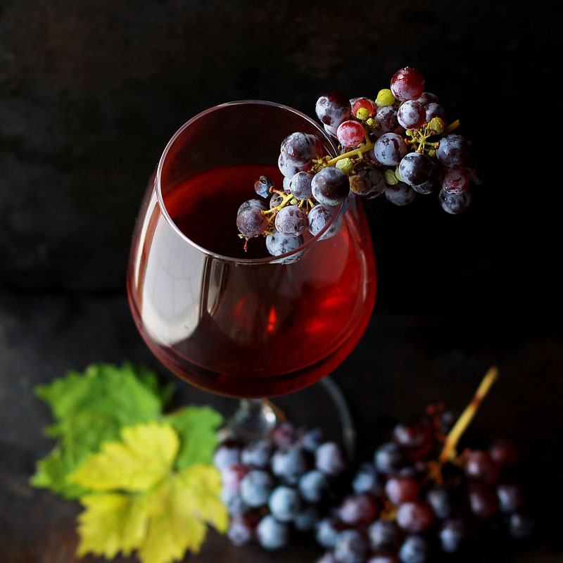 Glass of red wine next to a bunch of grapes